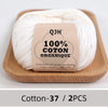 A ball of white organic cotton yarn labeled QJH 100% COTON ORGANIQUE on a wooden board.