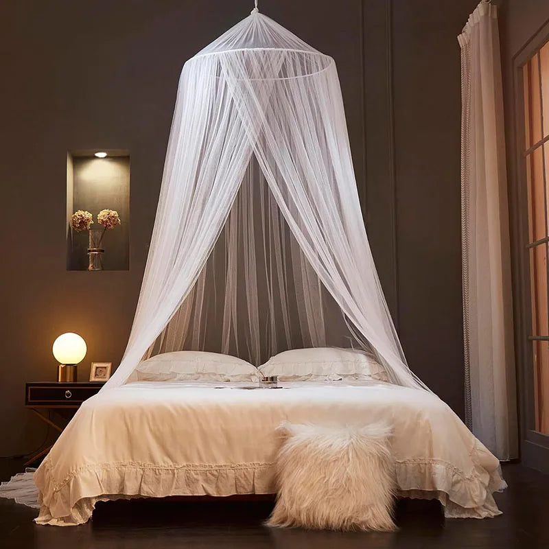 A sheer white mosquito net canopy draped over a bed in a dimly lit room.