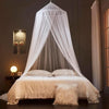 A sheer white dome mosquito net draped over a bed, creating a private sleeping enclosure.