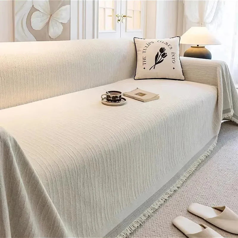A light beige elegant jacquard sofa cover blanket draped over a sofa with decorative pillows and natural light.