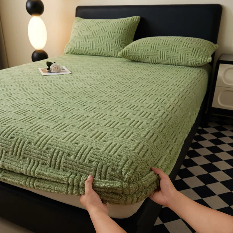 A close-up of a green plush jacquard mattress cover on a bed with matching pillows and a black and white patterned floor.