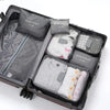 A dark gray travel packing cube set with five individual pouches visible inside the open suitcase.