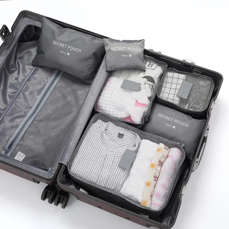 A dark gray travel packing cube set with five individual pouches visible inside the open suitcase.