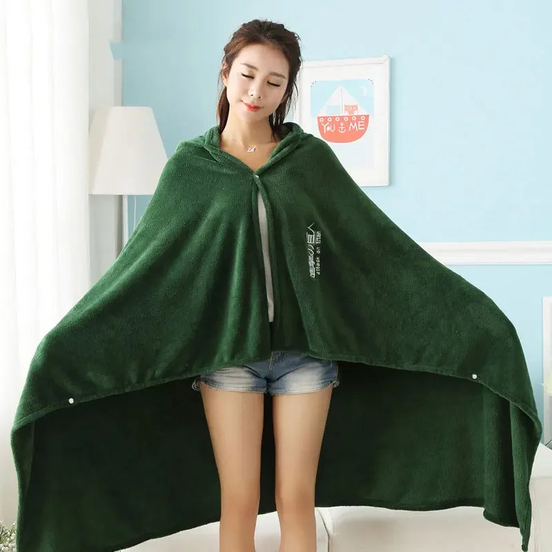 A woman models a dark green Attack on Titan Survey Corps flannel cloak with hood over denim shorts.