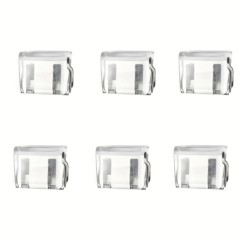 Four clear plastic invisible edge clips used for adjusting pants hems.