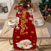 A festive red table runner decorated with gold stars and Santa Claus imagery, set on a wooden table.