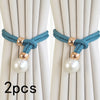 Two sets of teal cord curtain tie-backs with gold accents and pearl beads against a light fabric background