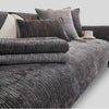 A close-up of a dark gray geometric chenille sofa cushion cover with matching pillows and throws.