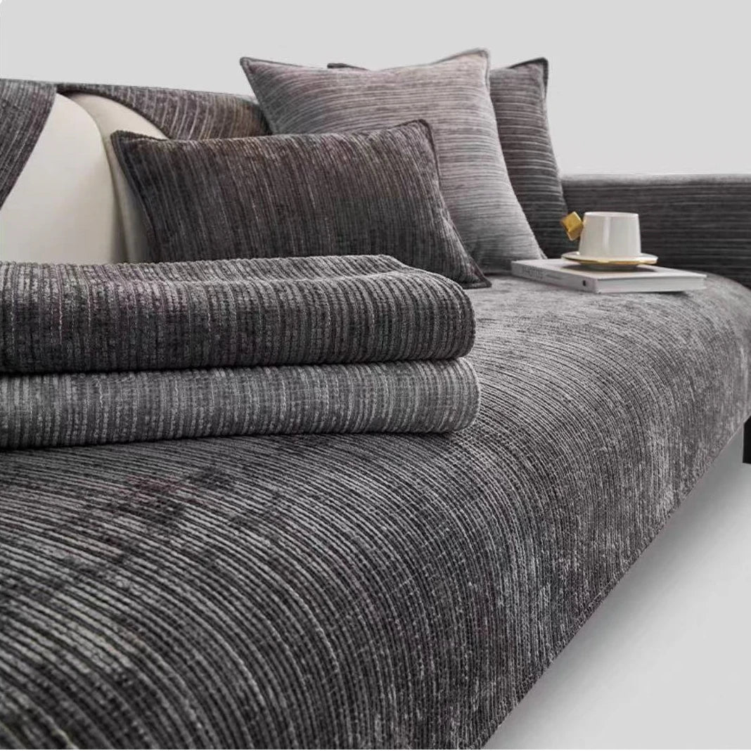 A close-up of a dark gray geometric chenille sofa cushion cover with matching pillows and throws.