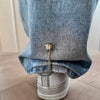 Close-up of denim jeans cuff featuring a gold magnetic chain buckle detail.