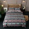 A patterned duvet cover set featuring geometric bohemian designs in shades of purple, pink, and black on a bed.