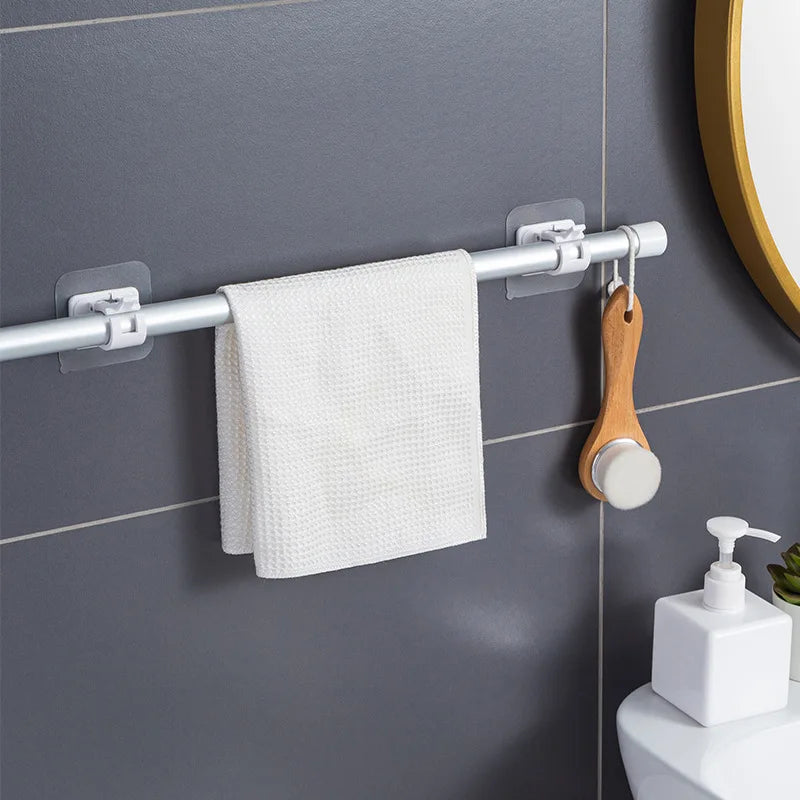 A silver curtain rod with hooks is mounted on a gray tile wall, holding a white hand towel.