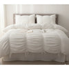 A pure white princess ruffle cotton bedding set with pillows and a duvet on a bed.