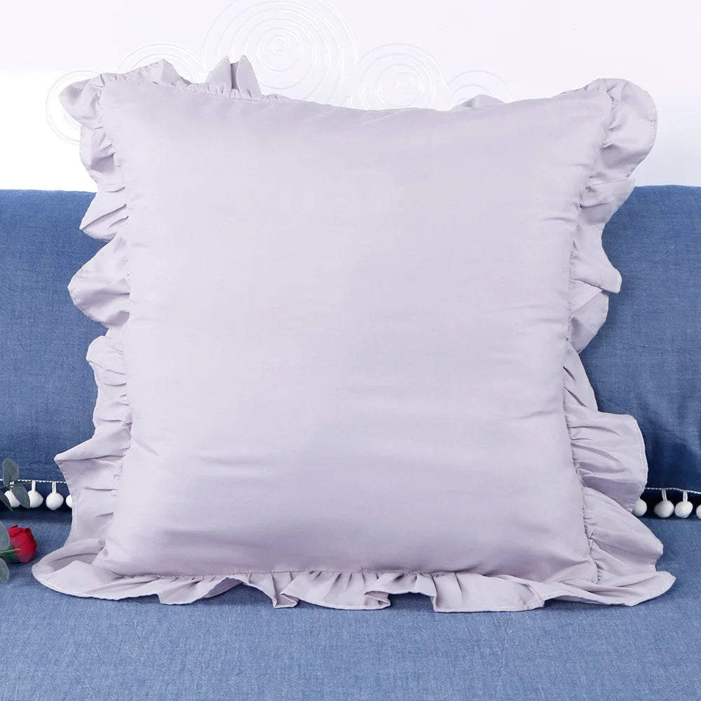 A light lavender ruffled pillow cover displayed on a blue fabric surface.