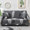 A gray sofa covered with a floral leaf print fabric, featuring white and dark green patterns.