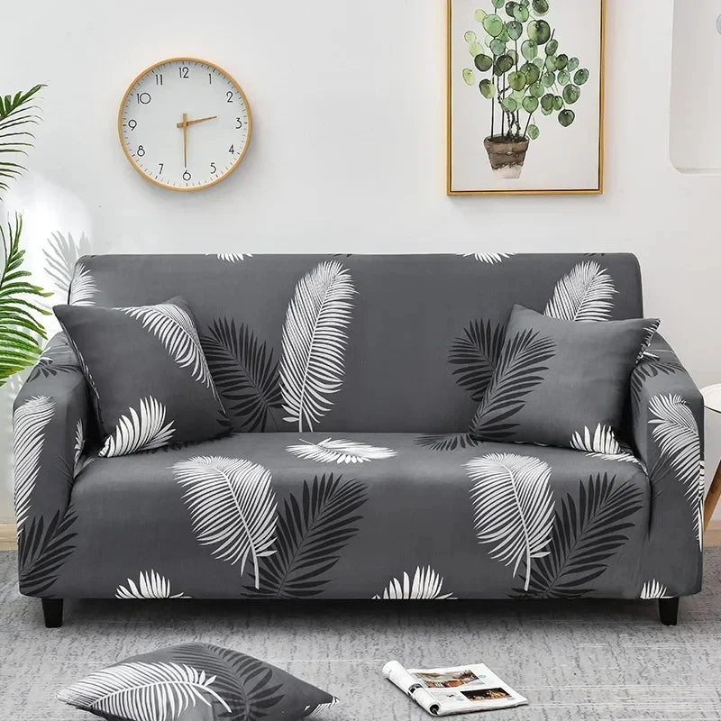 A gray sofa covered with a floral leaf print fabric, featuring white and dark green patterns.