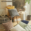 A cozy living room scene featuring a warm plush pillow cover in gray and yellow tones on a wooden chair.