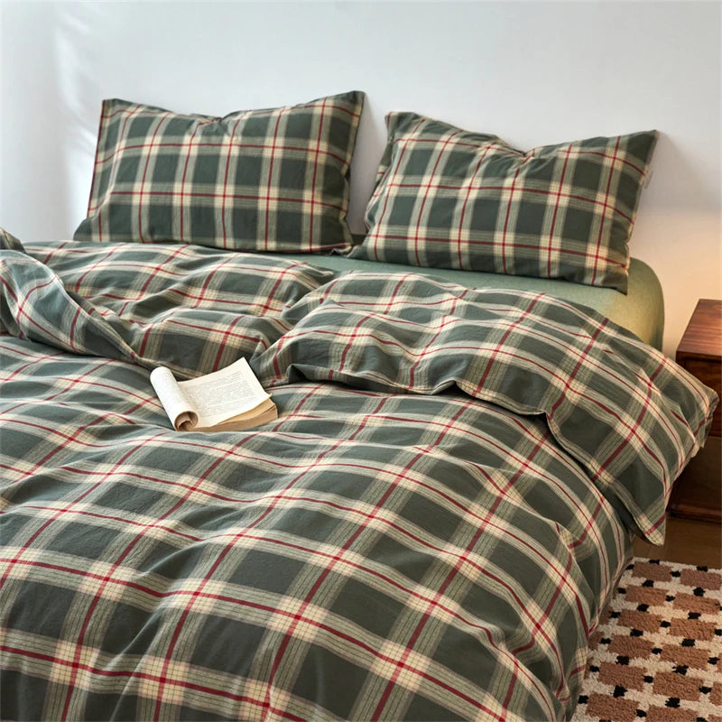 A plaid duvet cover set in olive green and burgundy tones with a muted tartan pattern on a bed.