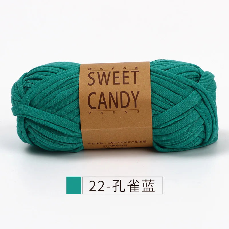 A skein of teal green hand-dyed fabric strip yarn labeled Sweet Candy Yarns.