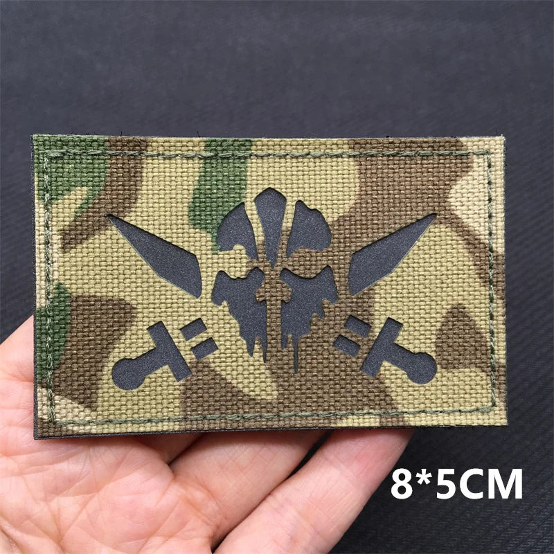 A rectangular tactical patch featuring a camouflage pattern with a stylized national flag design.
