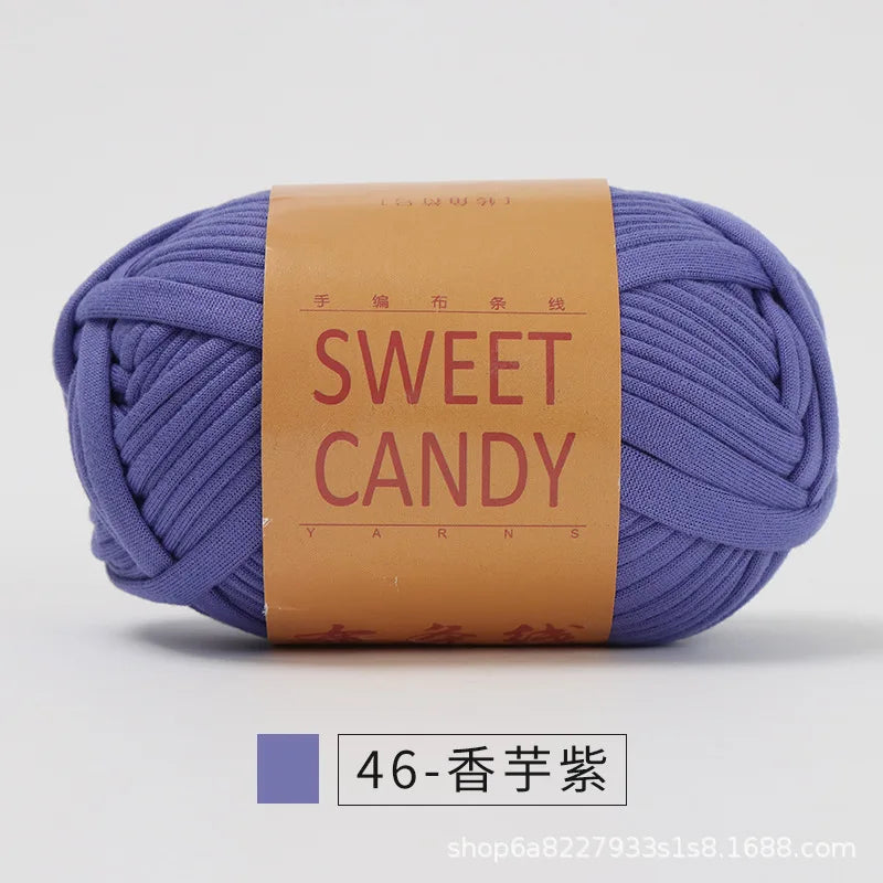 A ball of purple hand-dyed fabric strip yarn labeled SWEET CANDY