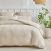 A beige embossed leaf duvet cover set displayed on a bed with white headboard and natural light.
