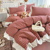 A plaid duvet cover set featuring red and white checks with lace embroidery displayed on a bed.