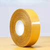 Roll of yellow no-sew hem tape with a white core on a light wooden surface