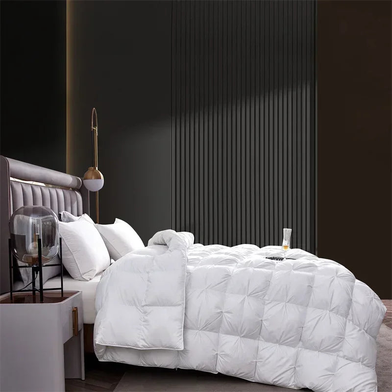 A white luxury goose down quilt duvet is displayed on a bed with dark gray and brown accents.