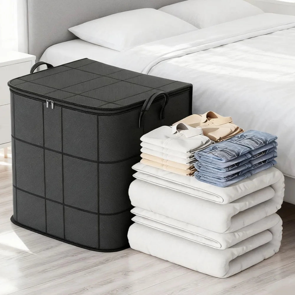 A black portable folding storage bag is placed next to a white bed with folded white and blue textiles.