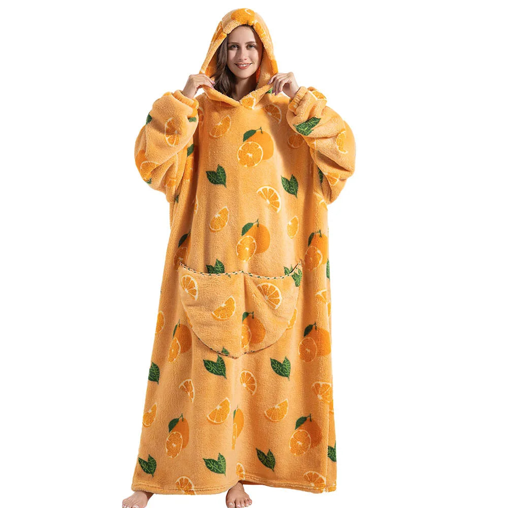 A woman wearing an oversized orange sherpa fleece blanket hoodie with a hood and fruit print.