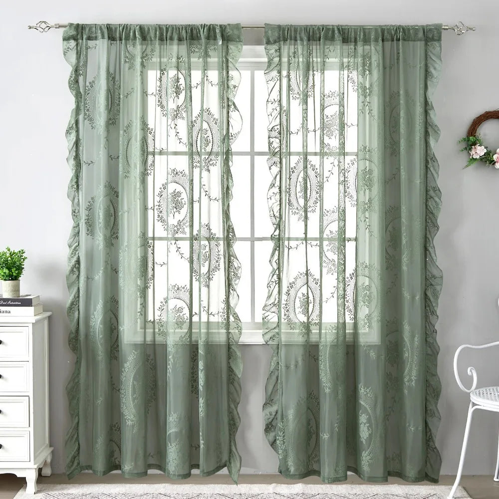 A pair of sheer, sage green floral lace curtains hanging in a window.