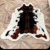 A white faux animal skin rug with dark brown and black markings on a light wood floor.