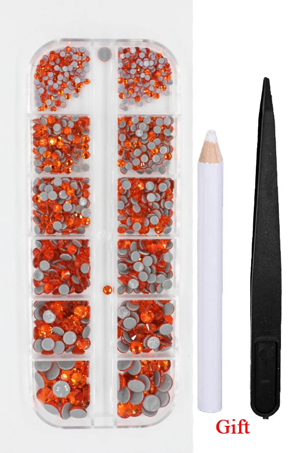 A clear plastic case containing a set of orange and silver crystal hot fix rhinestones and an applicator tool.
