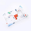 A white muslin swaddle blanket featuring various colorful seasonal and nature-themed designs.