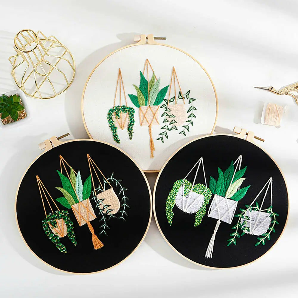 Two circular embroidery hoops display floral cross stitch designs on white and black fabric.