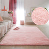 A pink plush area rug is laid on a light wood floor in a bright room with sheer curtains and a large circular pink rug.