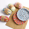 A collection of hand-dyed fabric strip yarn in various colors and textures, including skeins and a circular crochet item, dis