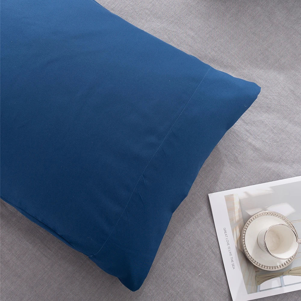 A deep blue microfiber pillow cover is shown on a light gray fabric surface.
