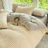 A beige and cream checkered duvet cover set with a soft gray throw pillow on a bed.
