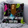 A decorative pillow cover featuring a bold, colorful print with text that reads BAPE STORE LAS VEGAS NOW OPEN