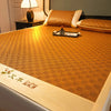 A close-up of a natural bamboo cooling mat with an orange patterned surface resting on a bed.