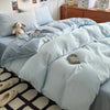 Light blue ultra-soft washed cotton quilt bedding set on a bed with a wooden dresser in the background.