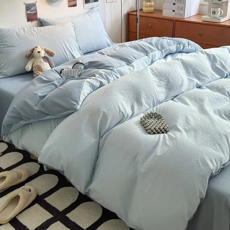 Light blue ultra-soft washed cotton quilt bedding set on a bed with a wooden dresser in the background.
