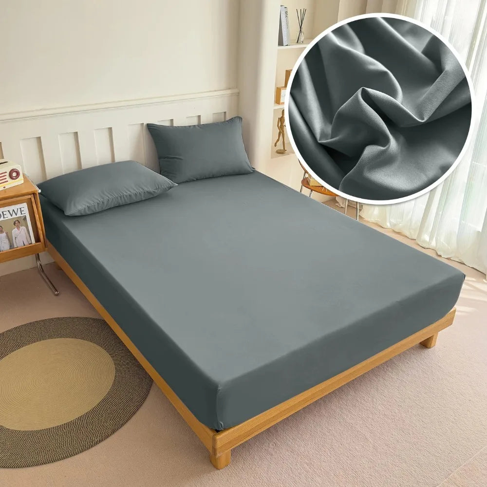 A gray universal fitted bed sheet set displayed on a bed with pillows and a rolled fabric swatch.
