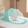 A light mint green foldable mosquito net canopy is set up over an infant cot for protection.