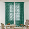 A pair of dark green vintage floral lace curtain panels hanging over a white window.