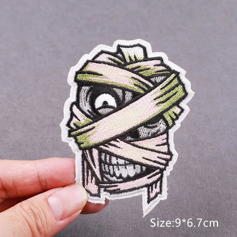 Embroidered horror movie patch featuring a stylized, menacing face wrapped in beige and green fabric.
