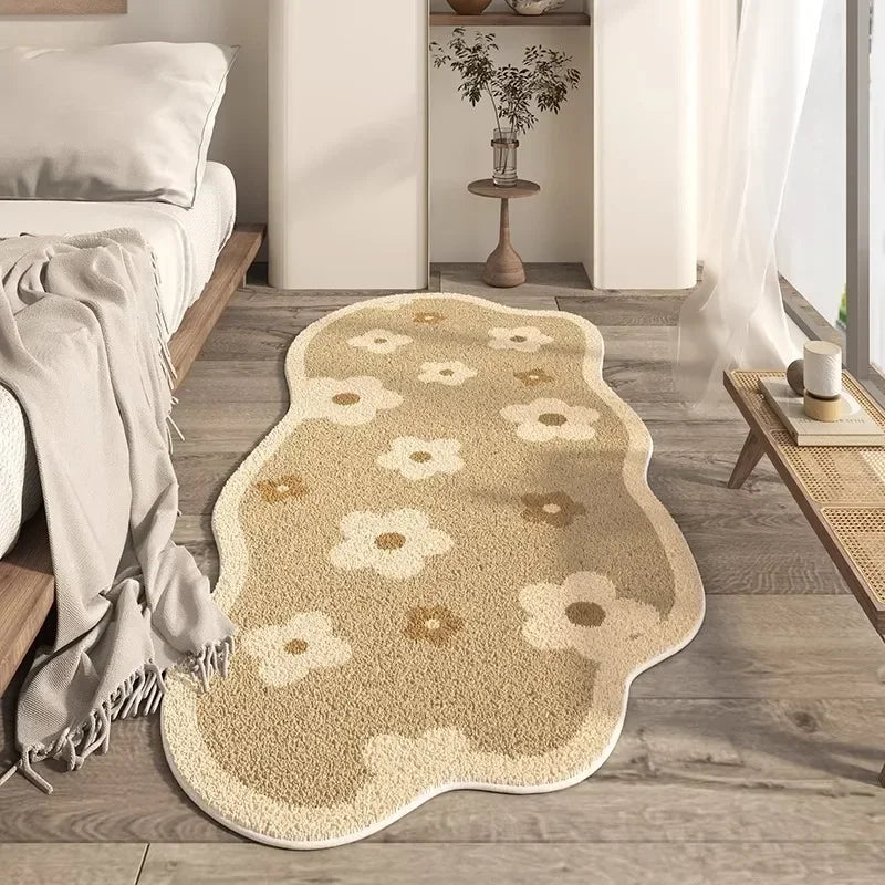Irregular plush cream area rug with subtle floral pattern placed on a light wood floor near a bed.