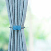 Blue decorative curtain tiebacks with a magnetic rope securing light blue fabric curtains.